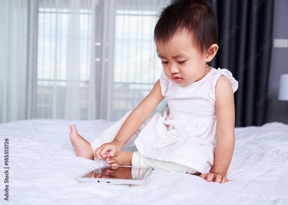 Fototapeta premium baby are looking to play and read tablet computer on bed