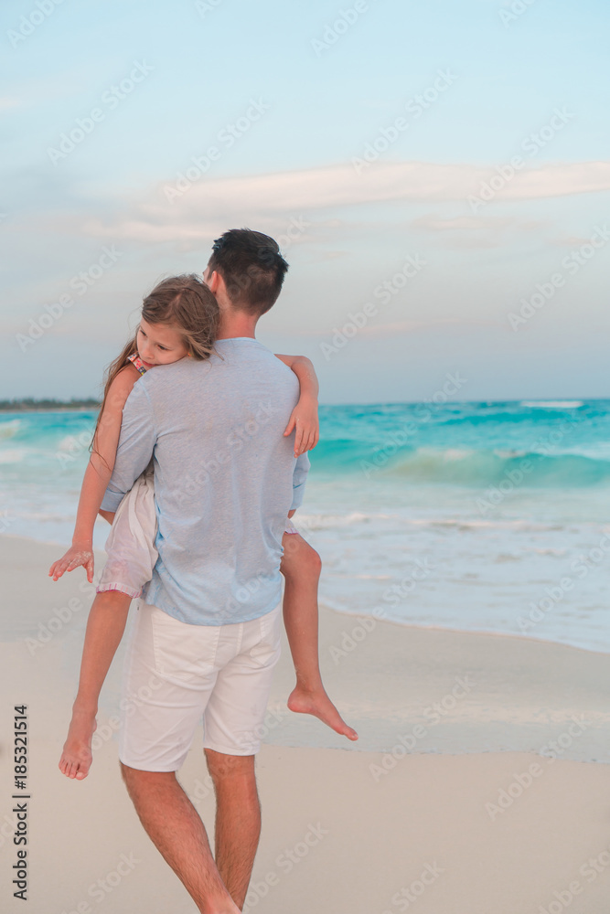 Adorable girl and young father at tropical beach. Family in the evening on the beach Adorable girl and young father at tropical beach. Family in the evening on the beach