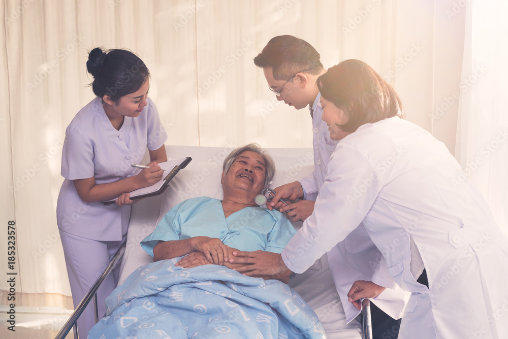 Fototapeta premium Elderly patient lying on bed with Doctors and nurse consulting for encouraging in treatment at hospital ,Health care and people concept