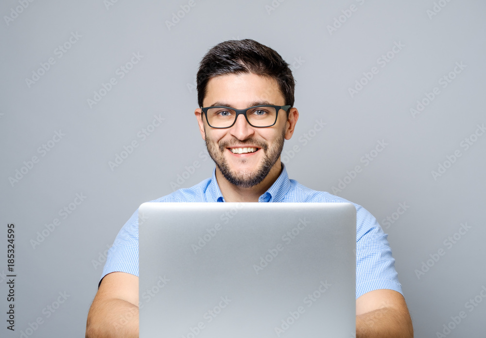 Portrait of young smiling man sitting at the desk with laptop Portrait of young smiling man sitting at the desk with laptop