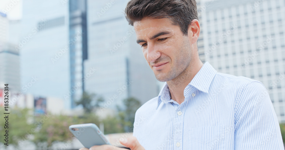Caucasian businessman look at mobile phone in city Caucasian businessman look at mobile phone in city
