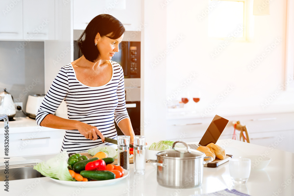 Beautiful woman standing in the kitchen and cooking