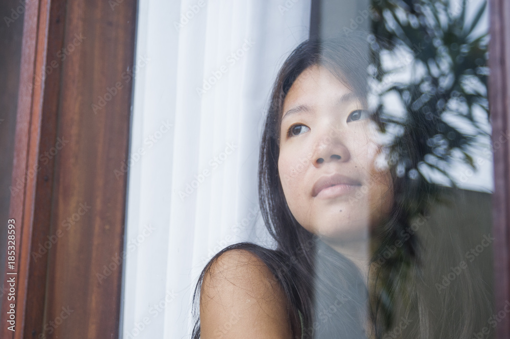 young sad and depressed Asian Chinese woman looking thoughtful through window glass suffering pain and depression in sadness concept young sad and depressed Asian Chinese woman looking thoughtful through window glass suffering pain and depression in sadness concept