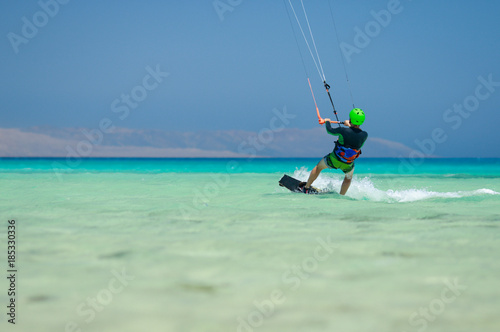 Kiteboarding beginner rider with kite in skies, sea view, blue lagoon,beautiful landscape with sea blue water, sandy beach coastline and mountains view on the horizon line, uninhabited islands