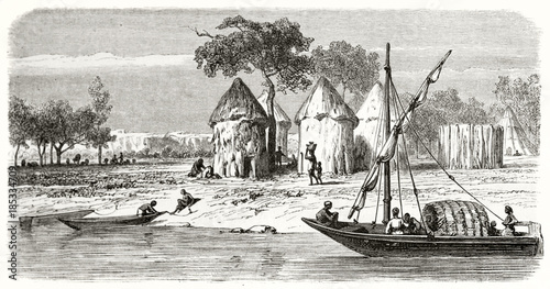 Ancient African village life along the shore of White Nile in Sudan while a sail boat is passing on the right. Created by Girardet and Levy after Bolognesi published on Le Tour du Monde Paris 1862 photo