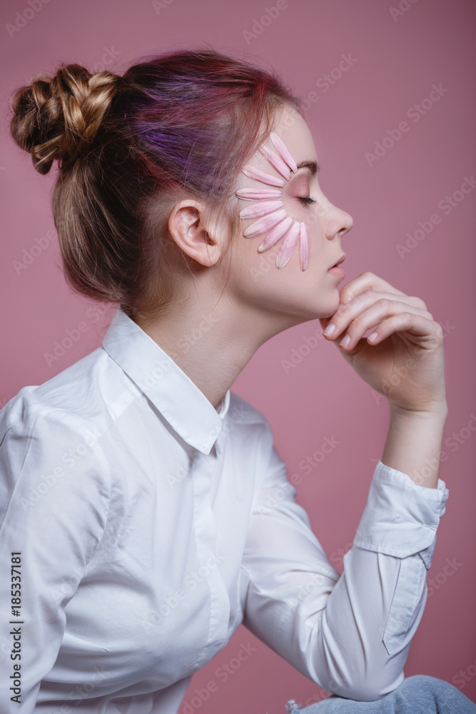 Portrait of beautiful young woman looking at camera with a flower. Close up face of beauty girl with flower gerbera on pink background. Skin care and beauty concept.