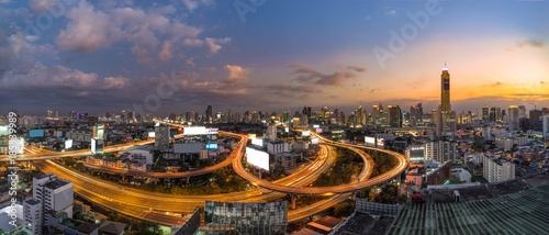 Panoramic Bangkok City with Curved Express Way and Skyscraper. Top View of City Elevated Highway with Car Traffic Light Trial at Twilight Time.
