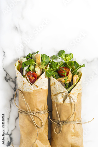 Fresh tortilla wraps on a marble pattern tabletop tied round with brown paper and string. Top view shot. Gourmet conception.