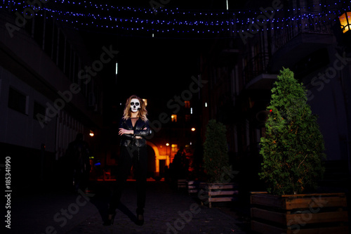 Halloween skull make up girl wear in black at night street of city.