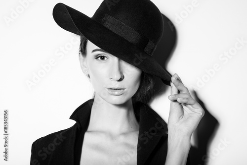 high fashion portrait of elegant woman in black and white hat and dress. Studio shot