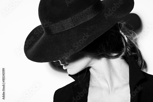 high fashion portrait of elegant woman in black and white hat and dress. Studio shot