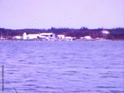 Sailboat riding through channel markers off Cape Cod coast during summer of 1976