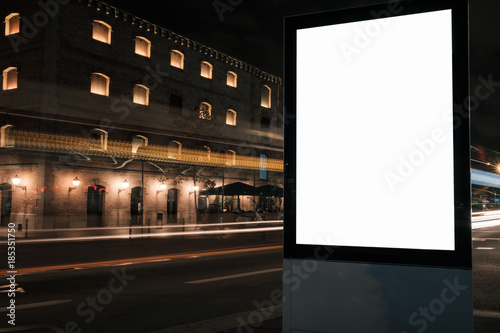 Fototapeta Naklejka Na Ścianę i Meble -  Blank white advertisement lightbox at night. Mock-up design. Car light lines.