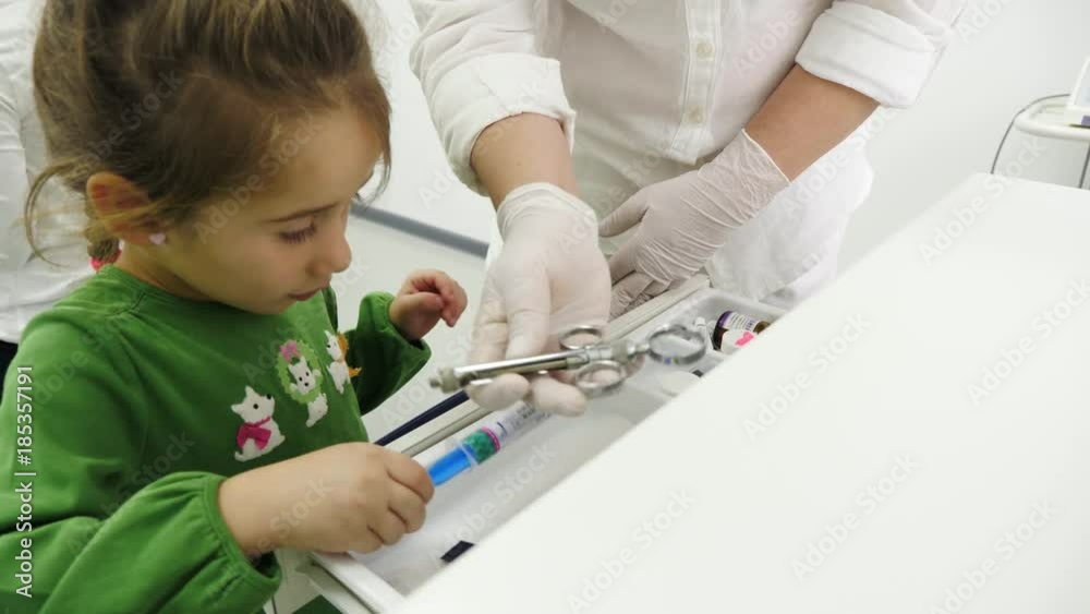 Little girl with dentist taken from the box a systems for dental anaesthesia. Little girl with dentist taken from the box a systems for dental anaesthesia.