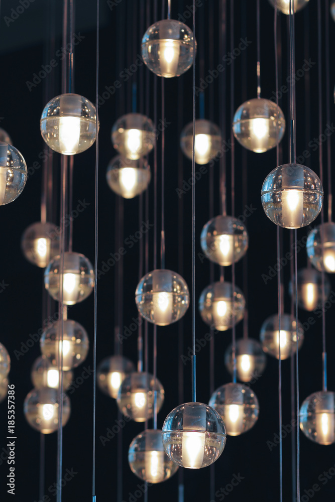 lighting balls on the chandelier in the lamplight, light bulbs hanging from the ceiling, lamps on the dark background, selective focus, vertical lighting balls on the chandelier in the lamplight, light bulbs hanging from the ceiling, lamps on the dark background, selective focus, vertical