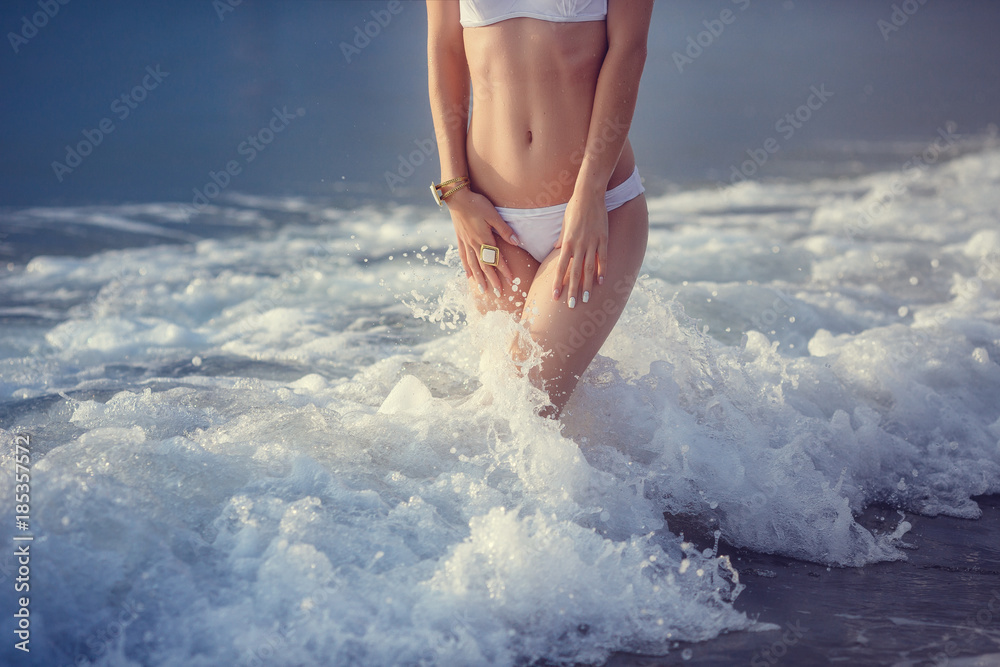 adorable sexy girl in bikini enjoying summer. outdoor portrait. Sea waves and white foam. Sunset after the rain on the island
