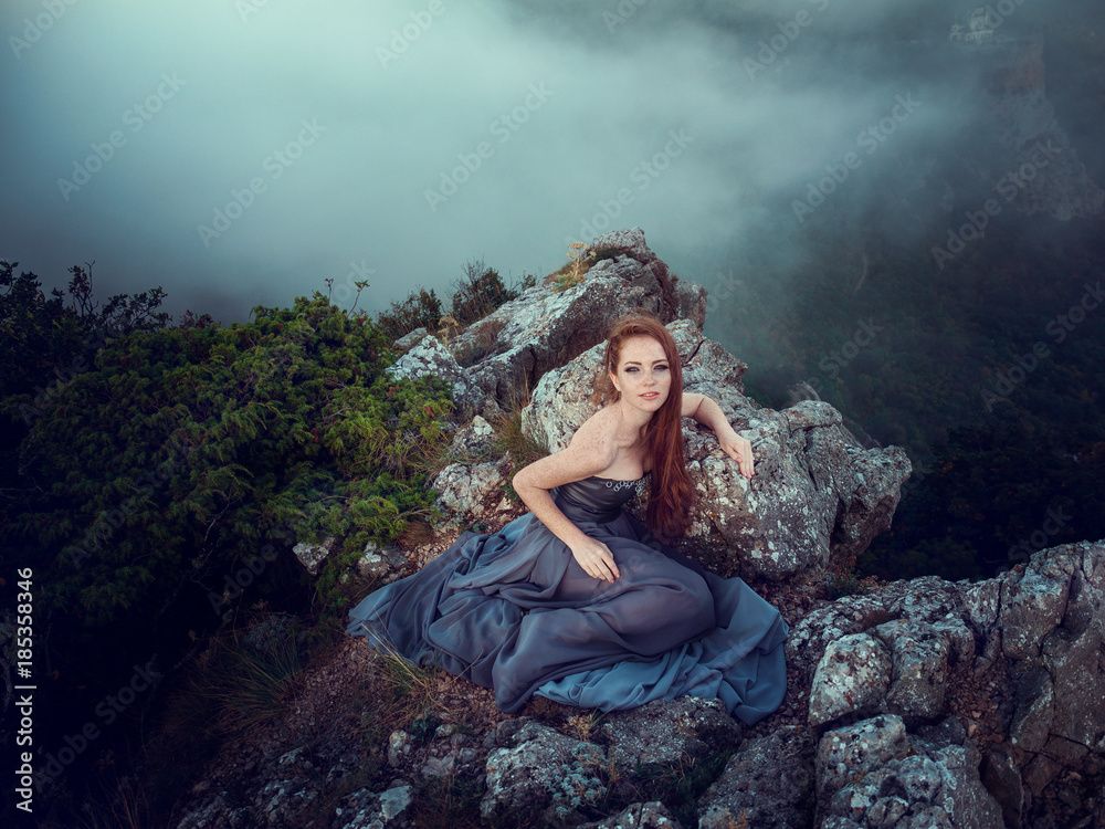 Naklejka premium Summer outdoors portrait of beautiful furious scandinavian warrior ginger woman in grey dress with metal chain mail.