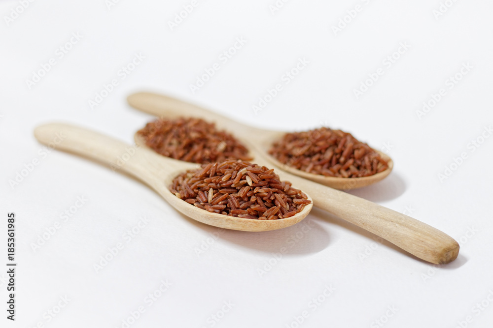 Thai Black or dark brown raw rice in a wooden spoon for a healthy diet. High fiber, vitamin, carbohydrate, minerals, and nutrition for healthy people. on the white background, isolate. Thai Black or dark brown raw rice in a wooden spoon for a healthy diet. High fiber, vitamin, carbohydrate, minerals, and nutrition for healthy people. on the white background, isolate.