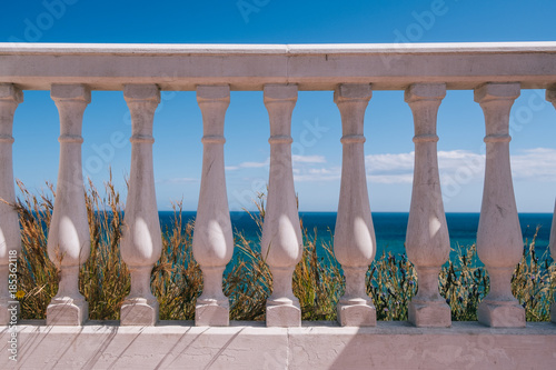 White fence on sunny day with blue sea and sky in background