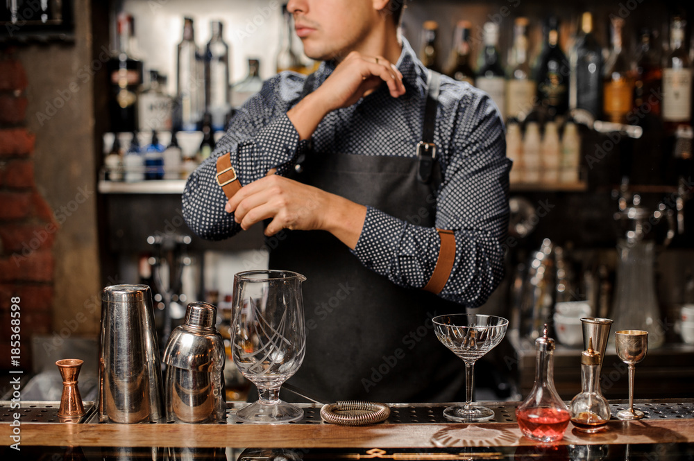 Bartender standing behind the bar counter with a bar equipment Bartender standing behind the bar counter with a bar equipment