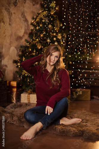 Beautiful girl in a sweater next to the Christmas tree/new year