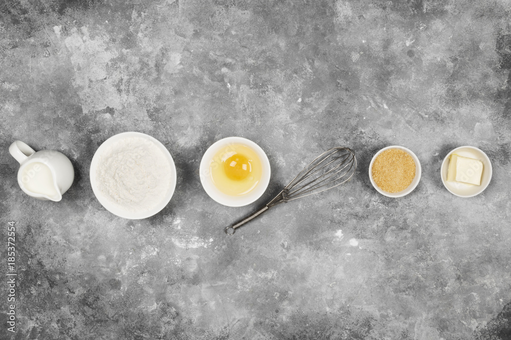 Ingredients for pastries - flour, eggs, butter, milk, sugar on a gray background. Top view. Food background Ingredients for pastries - flour, eggs, butter, milk, sugar on a gray background. Top view. Food background