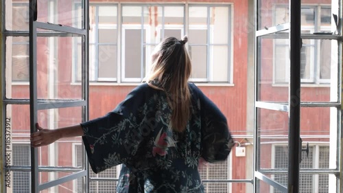 young woman indoors open window and stretching arms - waiking up, peaceful, relaxed concept photo