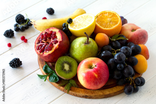 The concept of a healthy diet. Platter fruits and berries - orange, pear, apple, pomegranate, grapes, peach, apricot, blackberries and red currants. Vegan cuisine.