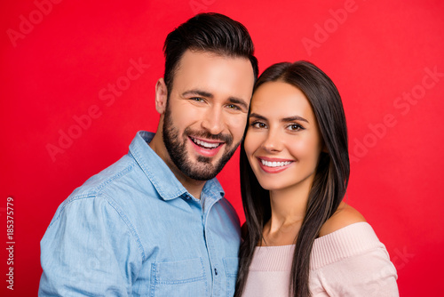 Close up portrait of smiling, beautiful, couple, looking at camera, head to head bonding, standing over red background, 14 february