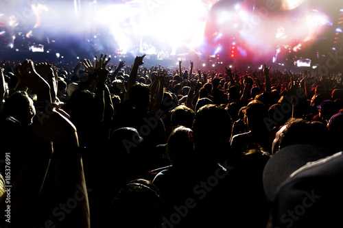 silhouettes of concert crowd in front of bright stage lights.