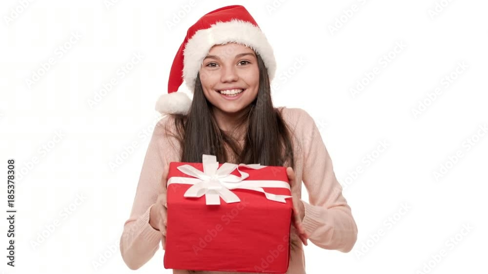 Portrait of excited female with very long hair wearing Santa Claus red hat being shocked to receive wonderful New Year present in gift wrap over white background. Emotions concept Portrait of excited female with very long hair wearing Santa Claus red hat being shocked to receive wonderful New Year present in gift wrap over white background. Emotions concept