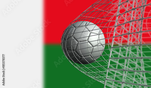 Soccer ball scores a goal in a net against Madagascar flag. 3D Rendering