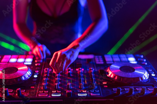 Motionblur of Dj hands on equipment deck and mixer with vinyl record at party