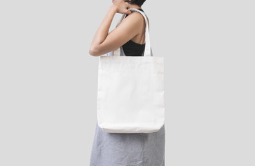 Girl is holding bag canvas fabric for mockup blank template isolated on gray background.