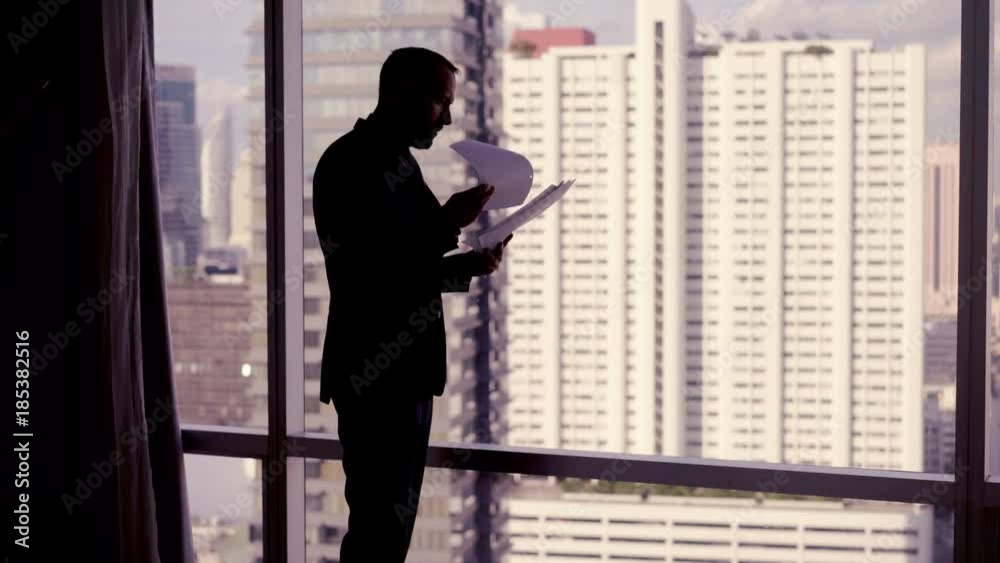 Sad, overwhelmed businessman standing with documents by window in the office, 4K
Sad, overwhelmed businessman standing with documents by window in the office, 4K
