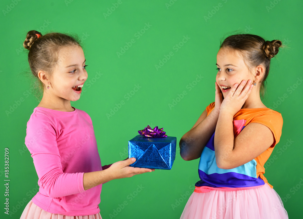 Girls with surprised faces pose with presents on green background. Girls with surprised faces pose with presents on green background.