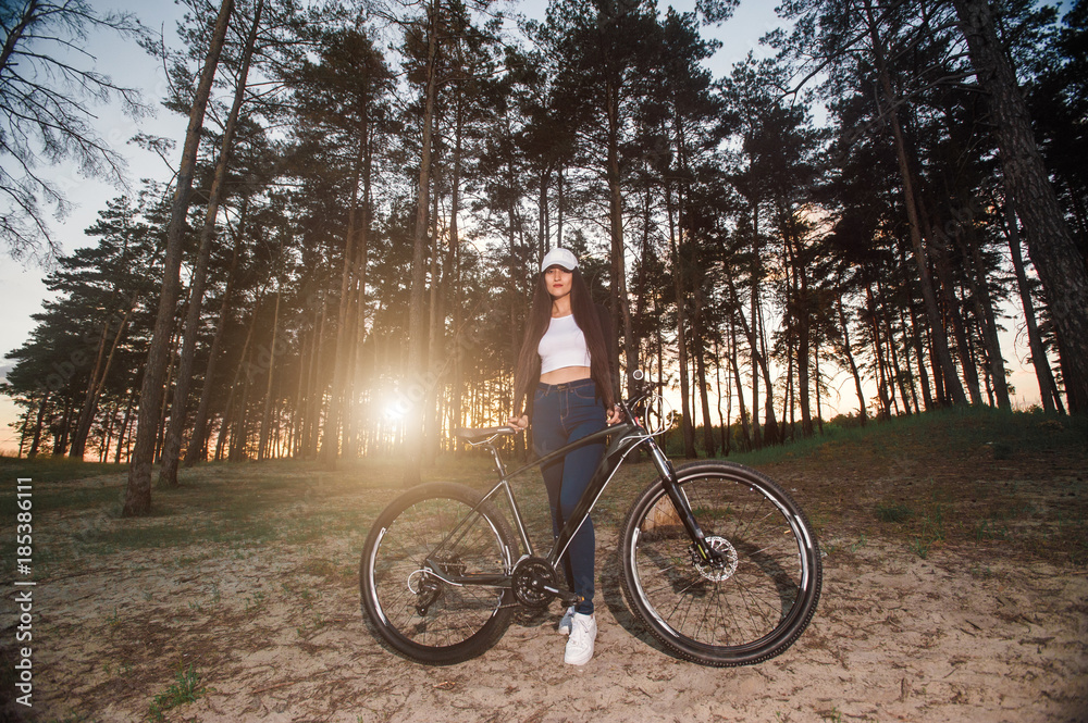 Biker girl at the sunset in forest.