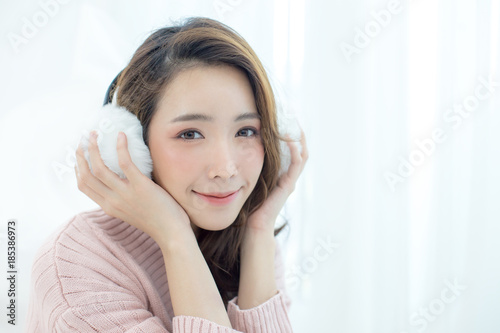 Attractive Asian Girl wearing sweater listen music with smile at home. Woman with winter concept.