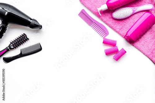 Women hair care set. Comb, shampoo, spray, curlers, hairdryer on white background top view copyspace