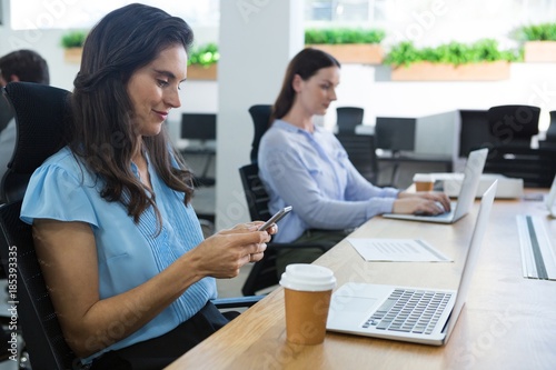 Female executive using mobile at desk