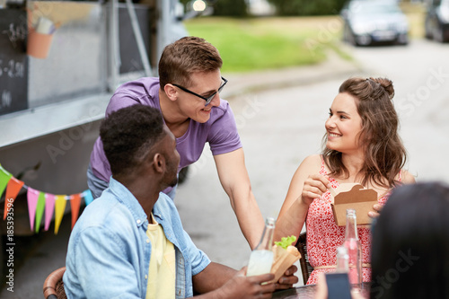 happy friends with drinks eating at food truck