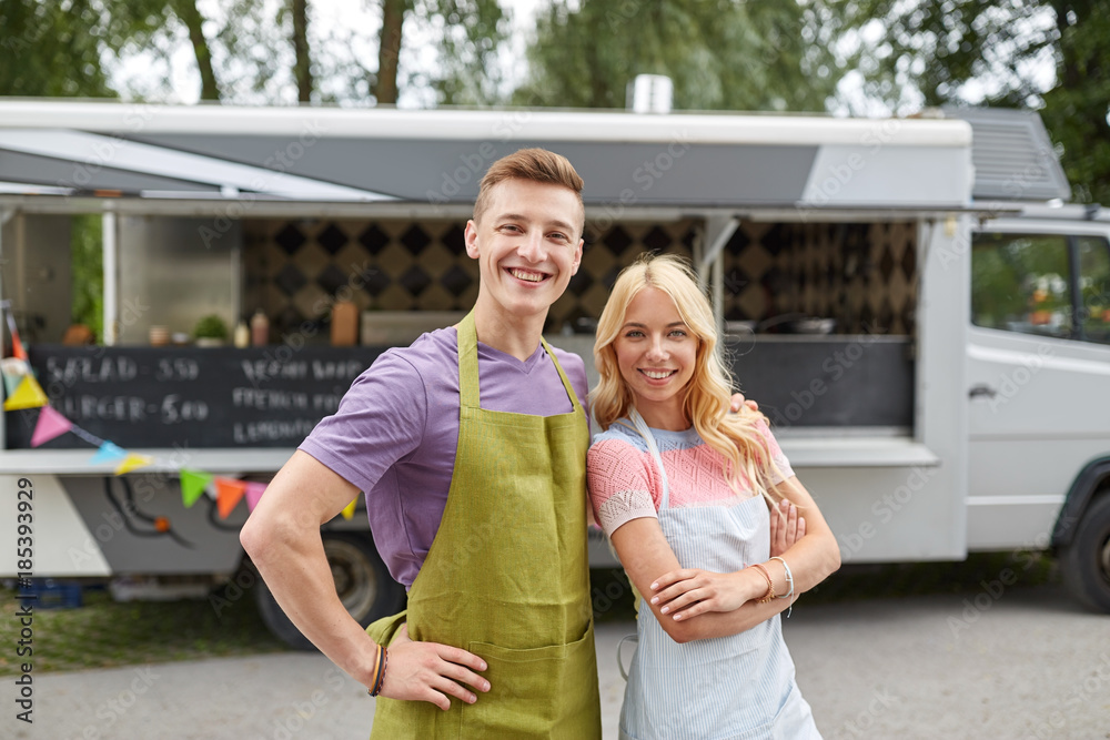 Naklejka premium happy couple of young sellers at food truck