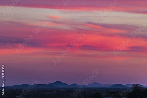 super pink horizontal clouds light up over a small town in the southwest © Brent Hall