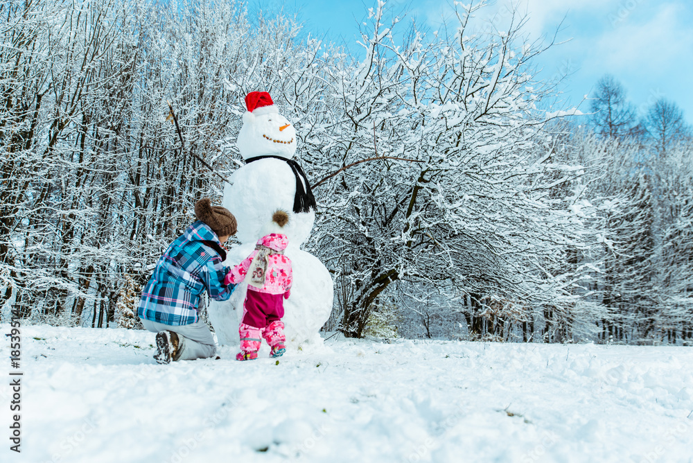 mother with daughter making snowman