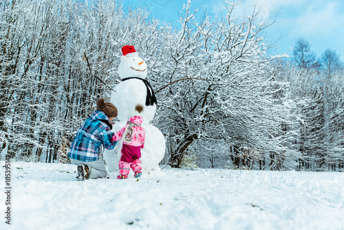 mother with daughter making snowman