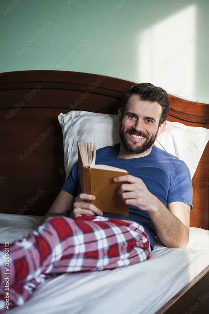 Young man reading a book in his bedroom