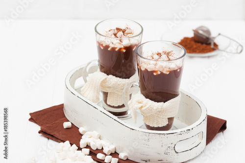 Warm cocoa in glasses with marshmallow, crocahet decorations, brown and beige napkins on white wooden background. Hot chocolate. Sweet drink. Close up photography. Hoizontal banner photo