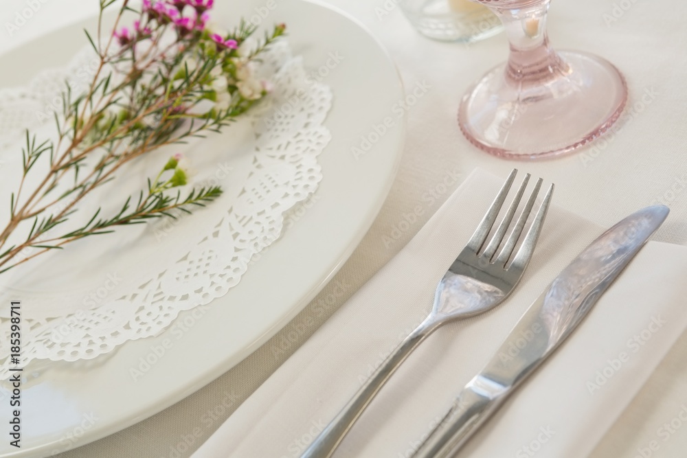 Flower kept over an embroidery napkin plate with cutlery Flower kept over an embroidery napkin plate with cutlery