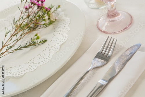 Flower kept over an embroidery napkin plate with cutlery