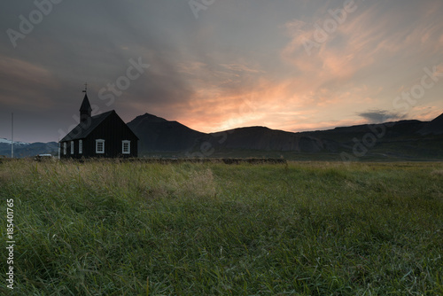 Black wooden church in front of a mountain chain